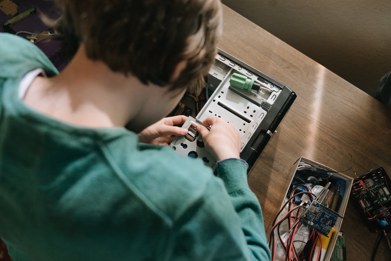 A young person working on computer hardware repair, showcasing hands-on technology skills.